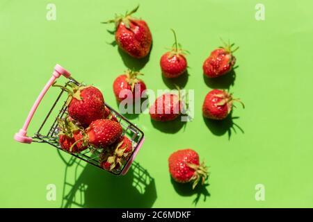 Panier rempli de fraises fraîches isolées sur des fraises vertes. Des fraises parfumées bio sucrées dans un mini-panier pour faire du shopping Banque D'Images