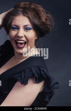 Studio portrait émotionnel d'une femme en surpoids. Elle crie dans le plaisir, sa main dans ses cheveux. Banque D'Images