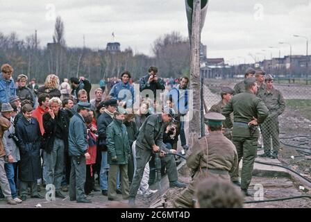 Une foule se rassemble sur le côté de l'Allemagne de l'ouest du mur de Berlin à la Potsdamer Platz à regarder comme la structure est démantelé. Banque D'Images