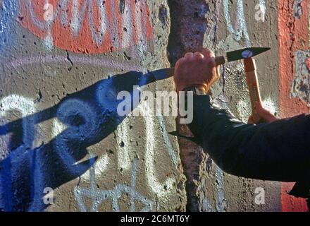 Un homme de l'Allemagne de l'Ouest utilise un marteau et un burin pour chip off un morceau du Mur de Berlin comme souvenir. Une partie du mur a déjà été démolis sur la Potsdamer Platz. Banque D'Images