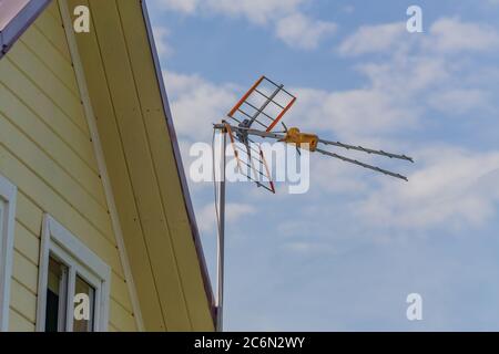 Antenne TV sur le toit d'une maison de campagne contre le ciel bleu Banque D'Images