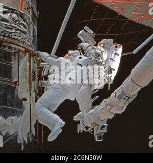 (11-21 février 1997) --- photographiés de l'intérieur de la cabine d'équipage de la navette spatiale Discovery, les astronautes Steven L. Smith (à gauche) et Mark C. Lee (bande rouge) inspectent l'isolation autour de la baie 10 du télescope spatial Hubble (HST) pendant l'une des cinq journées d'activités extravéhiculaires (EVA) conçues pour assurer le service de la TVH. Lee, commandant de charge utile, et Smith, ont exécuté trois des cinq EVA qui ont finalement été effectuées sur la mission. Banque D'Images