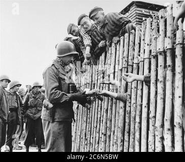 Le caporal Larry Matinsk de l'armée américaine met des cigarettes dans les mains étendues de prisonniers nouvellement libérés derrière un stock dans le camp de concentration d'Allach, près de Dachau Allemagne, le 30 avril 1945. On trouve également sur la photo les soldats américains Arthur Toratti et George Babel (deuxième et troisième à partir de la gauche). Allach était un sous-camp du camp de concentration de Dachau. Des soldats américains de la 7e Armée des États-Unis, y compris des membres de la 42e infanterie et de la 45e infanterie et de la 20e division des soldats de l'armée, ont participé à la libération de l'subcamp. Le principal camp de concentration de Dachau comptait plus de 120 sous-camps dans la région Banque D'Images