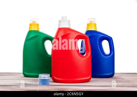Détergent liquide ordinaire de différentes variantes de parfum sur une surface en bois sur fond blanc Banque D'Images
