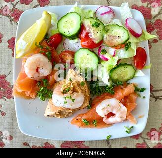 Salade de fruits de mer de luxe de crabe, saumon fumé et crevettes, avec une salade verte, un coin de citron et prêt à manger Banque D'Images