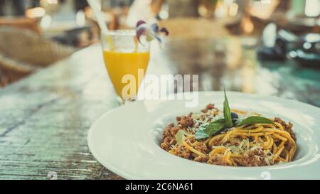 Nouilles appétissantes sur l'assiette et jus sur la table. De dessus de savoureux nouilles fraîches sur plaque blanche et jus d'orange dans le verre Banque D'Images