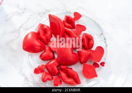 Fabrication de moules au chocolat en forme de baiser et d'entendre avec des bonbons rouges fond. Banque D'Images