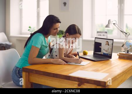 École en ligne. Une maman de famille et une fille de litle fait une leçon écoute l'enseignant à l'aide d'un ordinateur portable vidéo chat conférence assis à distance à la maison. Banque D'Images