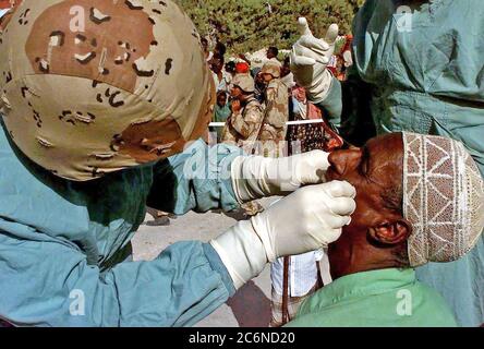 Un dentiste de la marine américaine (à gauche) examine les dents d'un homme en Somalie dans le cadre d'un programme d'action civique médicales effectuées dans les rues de Mogadiscio, en Somalie. Le dentiste est à partir de la Marine Expeditionary Unit, le Service de soutien Groupe 15, Camp Pendleton, en Californie. Cette mission est en appui direct à l'Opération Restore Hope. Banque D'Images