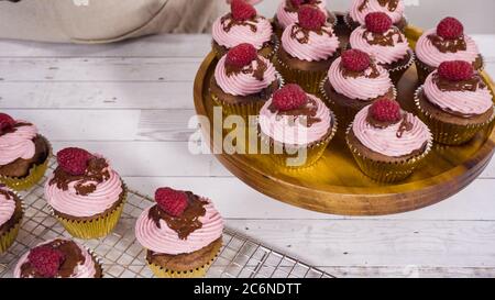 Des cupcakes au chocolat gourmets, arrosés de ganache au chocolat et recouverts d'une framboise fraîche. Banque D'Images