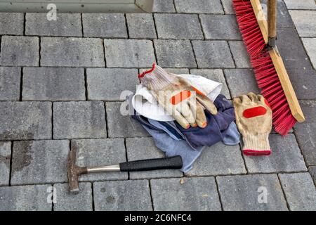 Dalles de chaussée en béton récemment posées. Le travailleur a mis le marteau, les gants, les T-shirts et le balai sur le même. Banque D'Images