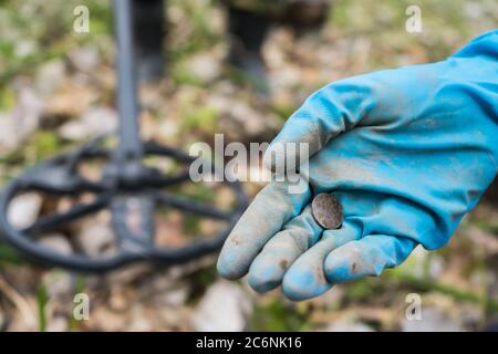 A trouvé une vieille pièce dans la main de l'ardigue. Un creuseur à gants en caoutchouc a trouvé une pièce de monnaie Banque D'Images