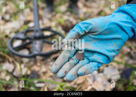 A trouvé une vieille pièce dans la main de l'ardigue. Un creuseur à gants en caoutchouc a trouvé une pièce de monnaie Banque D'Images