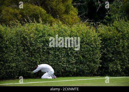 Un joueur de terrain recherche un ballon perdu pendant le match entre Pershore CC et Stratford-upon-Avon CC au The Bas, domicile du Pershore Cricket Club, Worcestershire. Banque D'Images