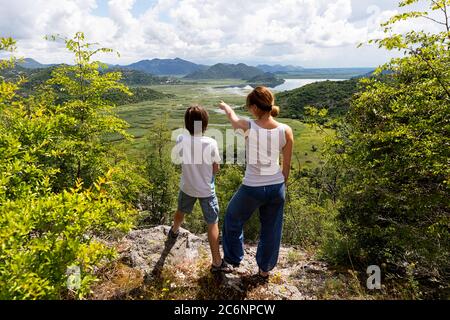 Vu de derrière les randonneurs modernes de mère et d'enfant en été pointant vers quelque chose, Rijeka Crnojevica, Monténégro Banque D'Images