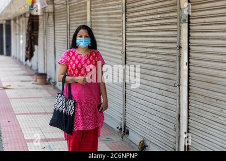 Femme indienne portant un masque de corona devant les magasins fermés sur la route Janpath à Connaught place Banque D'Images