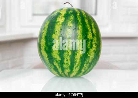 une pastèque entière se trouve sur une table dans une cuisine blanche Banque D'Images