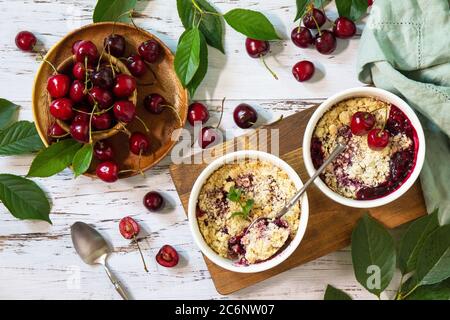 Dessert d'été fait maison. Crumble de cerise dans un plat de cuisson sur une table en bois. Banque D'Images