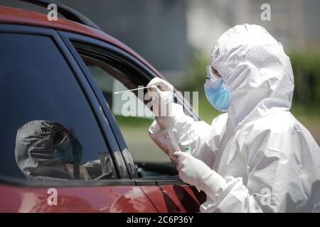 Bucarest / Roumanie - 11 juillet 2020 : un agent de santé utilise un test de RCP (écouvillon nasal et buccal) sur une personne à l'intérieur d'une voiture pour déterminer la présence ou l'abse Banque D'Images