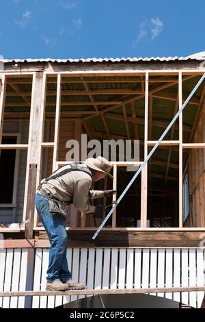 Menuisier travaillant sur l'ancien bois encadré haut style Queenslander maison pendant les rénovations Banque D'Images