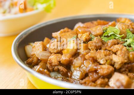 Remuez le porc frits avec de l'oignon et de l'ail et de la sauce au soja noir et de la garniture à la coriandre et du tofu avec lumière naturelle sur le cadre droit Banque D'Images