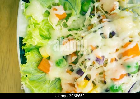 Salade saine comprend la carotte et le maïs et les petits pois, ainsi que la tomate et le chou avec garniture de mayonnaise et lumière naturelle sur le cadre droit en tons vintage Banque D'Images