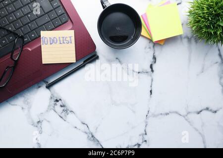 ordinateur portable et bloc-notes avec liste des tâches sur le bureau . Banque D'Images