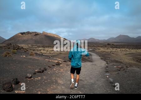 Un jeune homme marche le long du chemin vers le volcan 'El Cuervo' à Lanzarote, aux îles Canaries Banque D'Images