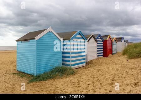 Une ligne de cabanes de plage sur une plage de sable en dessous un ciel spectaculaire Banque D'Images