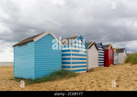 Une ligne de cabanes de plage sur une plage de sable en dessous un ciel spectaculaire Banque D'Images