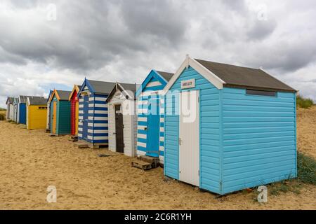 Une ligne de cabanes de plage sur une plage de sable en dessous un ciel spectaculaire Banque D'Images