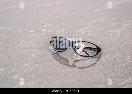 DÉBRIS DE PLAGE - VERS 2009. Lunettes de soleil cassées, en plastique, lavées sur une plage Banque D'Images