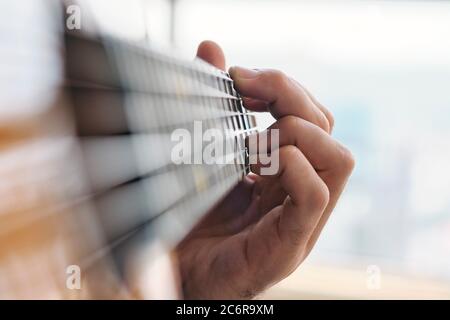 Gros plan sur l'homme pratiquant des accords avec la guitare classique Banque D'Images