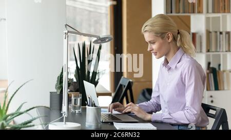 Jeune femme caucasienne travaillant sur un ordinateur portable au bureau Banque D'Images