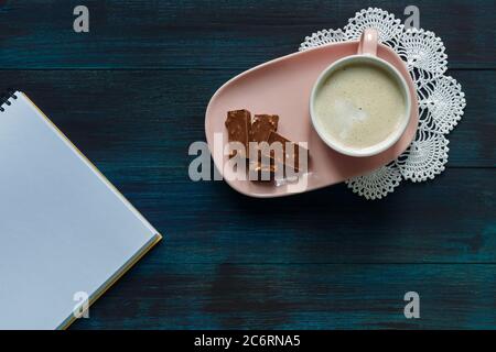 Tasse de café rose sur une assiette rose sur une serviette blanche crochetée au chocolat Banque D'Images