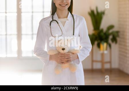 Gros plan médecin pédiatre souriant tenant le jouet moelleux dans les mains Banque D'Images