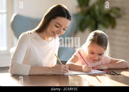 Femme souriante dessinant des crayons colorés avec une adorable petite fille Banque D'Images