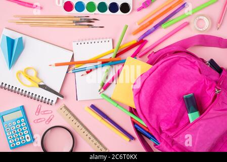 Se préparer au concept d'école. Vue du dessus de la tête photo de sac à dos rose et de papeterie colorée isolée sur fond rose pastel Banque D'Images