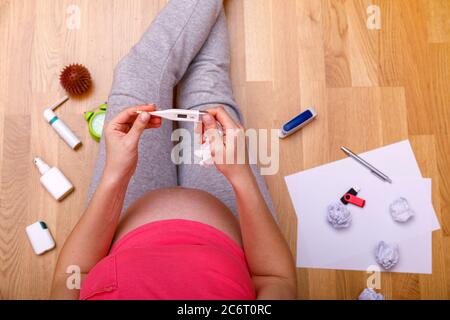 Femme enceinte portant un masque de protection COVID-19 ncov coronavirus. Assis près du lit avec des médicaments. Prévenir l'infection du fœtus. Gêne Banque D'Images