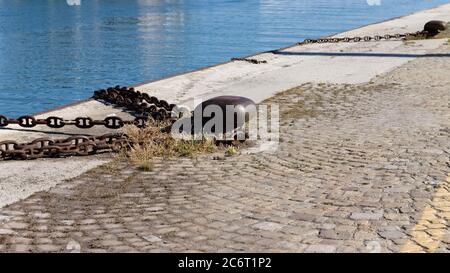 Bollard rouillé avec une chaîne de fer sur le quai du port (Pesaro, Italie, Europe) Banque D'Images