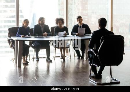 Les managers d'une heure multiraciale assis à la table à distance du candidat. Banque D'Images