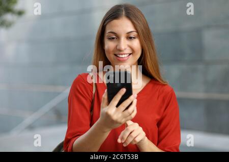 Portrait d'une femme souriante envoyant un message texte depuis son téléphone Banque D'Images