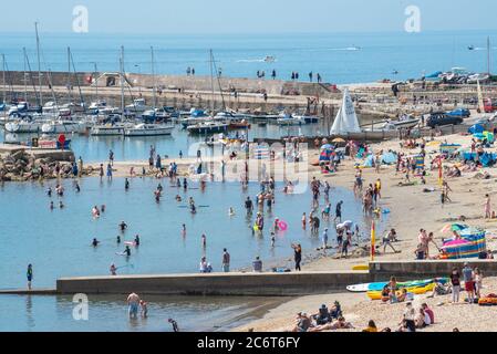 Lyme Regis, Dorset, Royaume-Uni. 12 juillet 2020. Météo au Royaume-Uni: La foule des amateurs de plage se rassemblent dans la station balnéaire pittoresque de Lyme Regis pour profiter du soleil brûlant. Ce week-end, les familles, les visiteurs et les amateurs de soleil ont fait le plein de la plage pour profiter du meilleur du temps ensoleillé tandis que les touristes rentraient un séjour agréable dans la station balnéaire populaire. Crédit : Celia McMahon/Alay Live News Banque D'Images