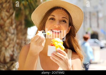 Gros plan de la jeune fille touristique qui mange de la glace traditionnelle italienne à Sirmione, en Italie. Jeune femme avec chapeau tenant la glace appréciant le look Banque D'Images