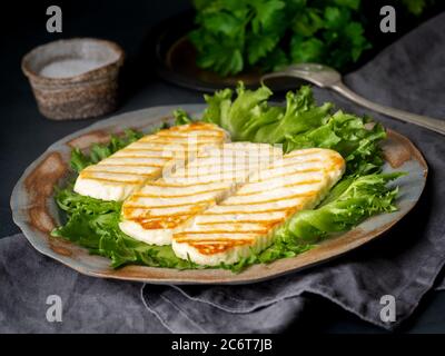 Halloumi grillé, fromage frit avec salade de laitue. Alimentation équilibrée sur fond sombre, vue latérale Banque D'Images