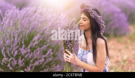 Jeune femme appréciant la vue et la lumière du soleil sur son visage sur un champ de fleurs rurales avec des fleurs de lavande. Photo de haute qualité Banque D'Images