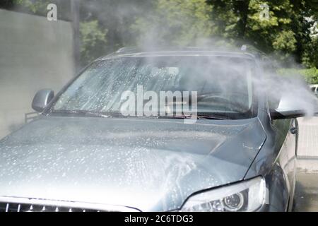 Lavage complet de voiture au libre-service. Gouttes d'eau éclaboussé par un pulvérisateur qui lave la voiture. Pare-brise. Mousse blanche Banque D'Images