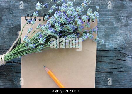 Livre ouvert avec papier blanc brun et bouquet de fleurs de lavande sur fond rustique gris en bois avec espace de copie. Vue de dessus, mise au point sélective Banque D'Images