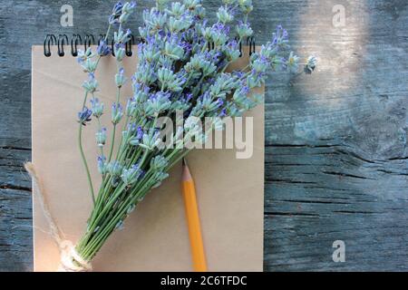 Livre ouvert avec papier blanc brun et bouquet de fleurs de lavande sur fond rustique gris en bois avec espace de copie. Vue de dessus, mise au point sélective Banque D'Images