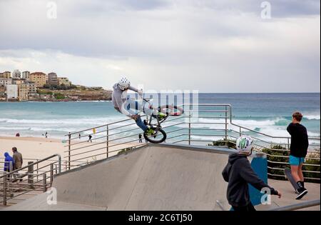 Un coureur helmetté faisant des cascades de vélo dans le parc de skateboard et de vélo sur Bondi Beach, Sydney Banque D'Images